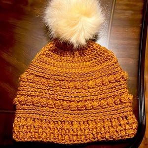 This is a hand crocheted hat with a large fluffy white Pom Pom